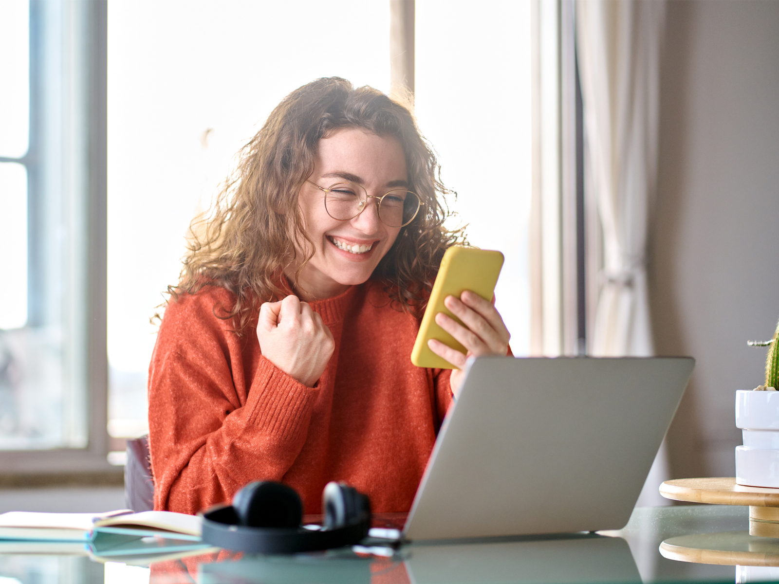 woman smiling at phone and laptop